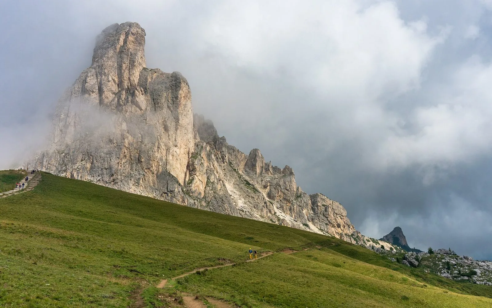 La Ra Gusela avvolta dalle nuvole sopra i prati verdi del Passo Giau, nelle Dolomiti