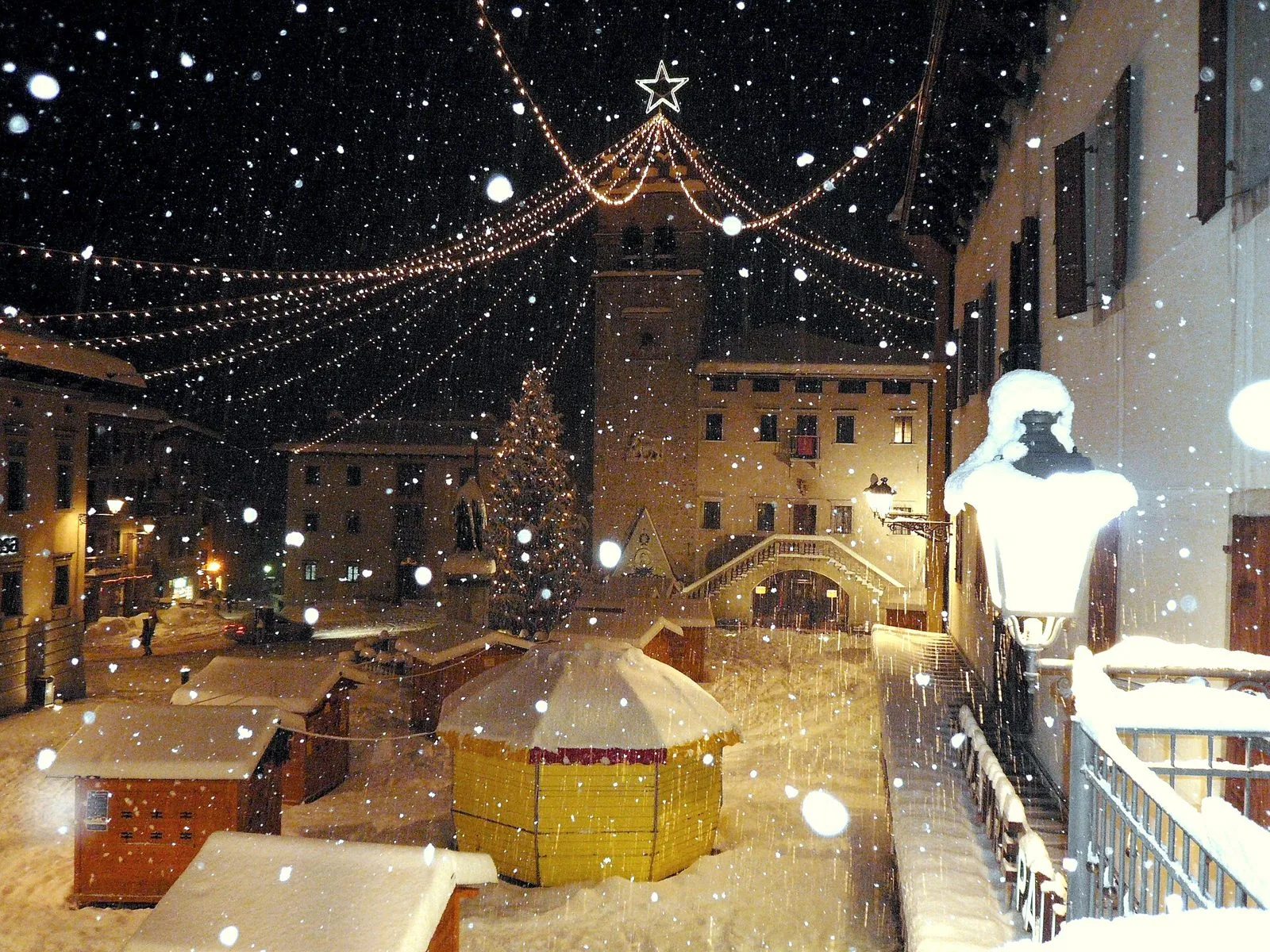 Piazza Tiziano a Pieve di Cadore sotto la neve, con il Palazzo della Magnifica Comunità illuminato di sera