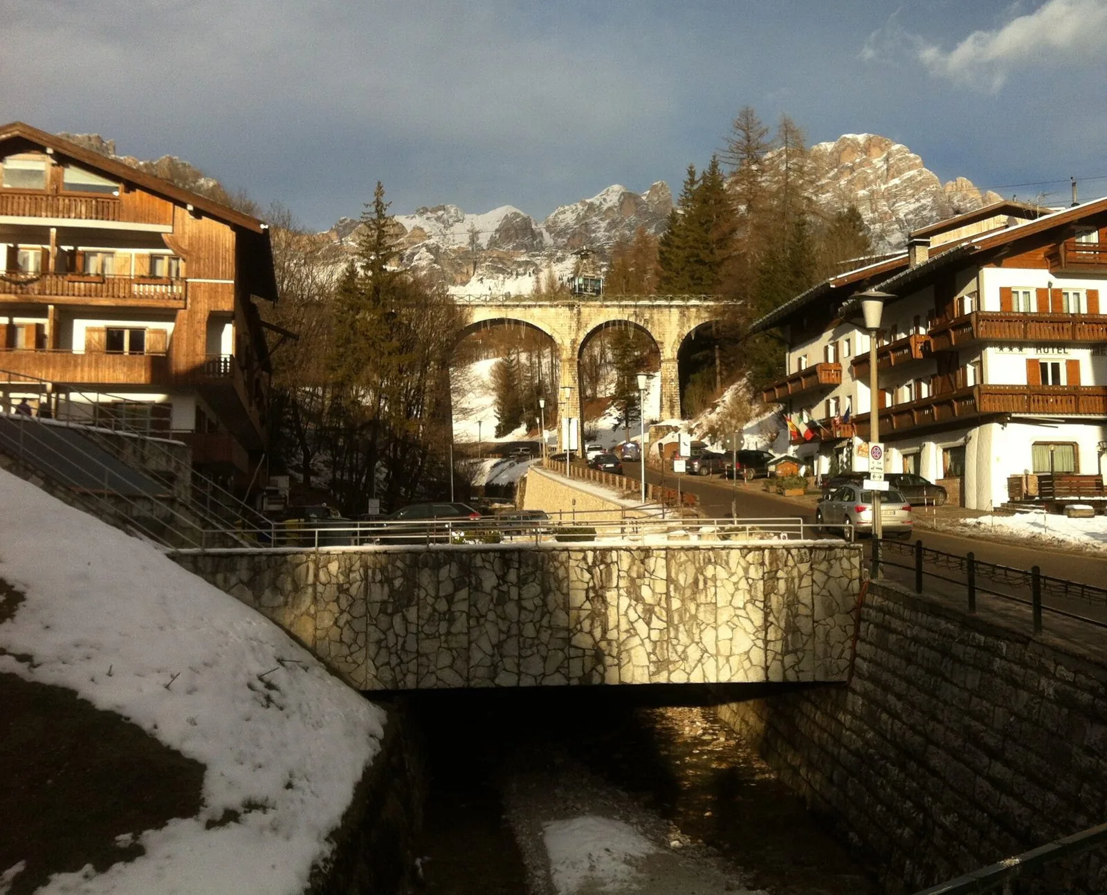Viadotto ad archi in pietra dell'ex ferrovia delle Dolomiti all'ingresso di Cortina d'Ampezzo, con le montagne innevate sullo sfondo